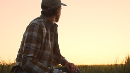 Farmer in front of a sunset agricultural landscape. Man in a countryside field. Country life, food production, farming and country lifestyle concept.