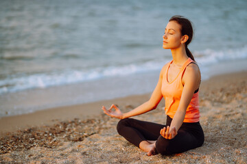 Fototapeta na wymiar Meditation. Young woman doing yoga near the ocean barefoot. Calmness and balance, a healthy lifestyle.