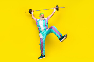 Full body portrait of excited sporty aged man have fun raise hold barbell up isolated on yellow...
