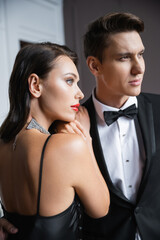 Young woman in silk dress hugging elegant boyfriend at home