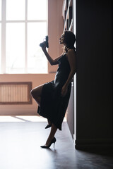 Side view of sensual woman in dress holding handgun at home