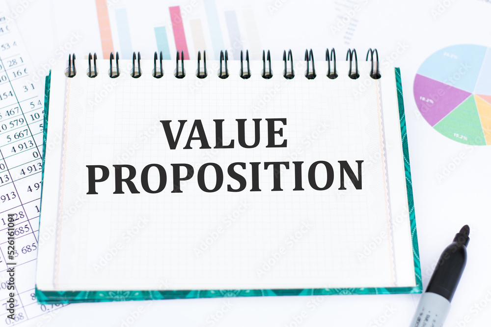 Aufkleber value proposition text on notepad on the background of reports and charts