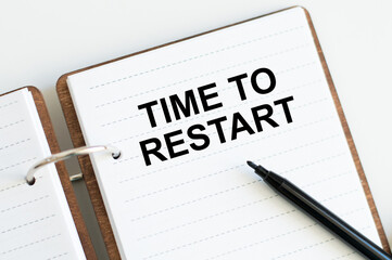 TIME TO RESTART text on a sheet of notepad paper on a light background next to a black marker