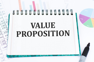 Value Proposition text on notepad on the background of reports and charts
