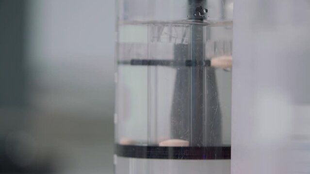 a tablet was thrown into a flask of water and dissolved by stirring water with a tablet. in the background flasks with leaves. close-up