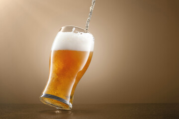 Stream of draught beer in glass on a beige background. Pouring lager beer in a glass. Glass of...