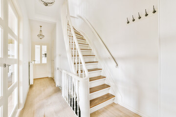 White hallway with wooden stairway leading to second floor of modern luxury apartment with...