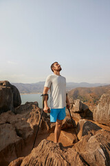 Disabled man standing on rock with crutches © Faces of Travel