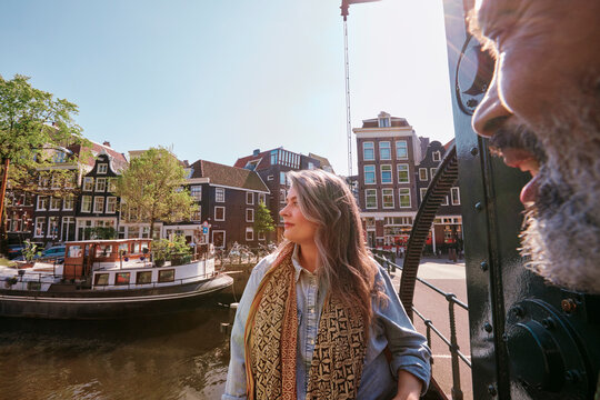 Mature woman looking away while standing by canal in Jordaan