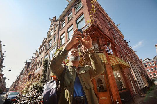 Mature man taking picture with smartphone in Jordaan