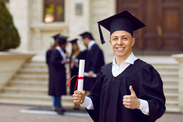 Portrait of joyful male university student with diploma who is doing excellent and approval sign....