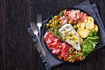 savory baked brie with crackers, salami, nuts, ham