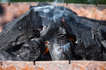 Close-up black burnt coal - smoldering firewood in the grill