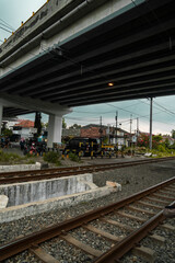 Fototapeta premium Details of railroad tracks made of iron, wood and gravel under an overpass, located in a densely populated suburban area
