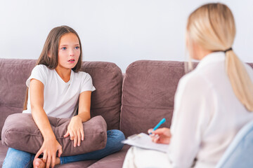 unhappy crying teenage girl talks to psychologist about her problems, hugging pillow, at home or in office, expressing emotions. sad child listens to psychologist, looking for way out of situation