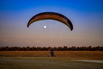 Paramotor con la luna al atardecer