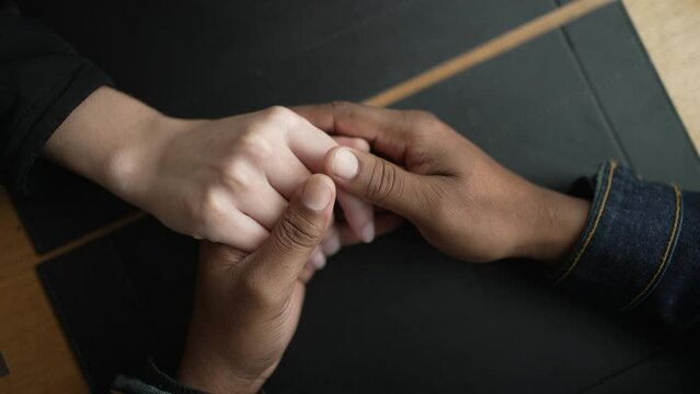 Young diverse couple hands closeup joining together in union. Romantic people holding hands in affection