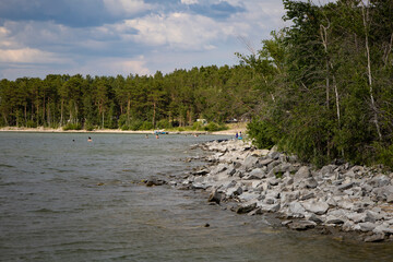 Rocky shore on a large lake in a wooded area.