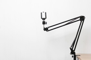Closeup shot of a black mic stand attached to the wooden table