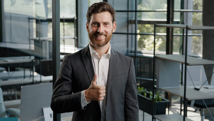 Bearded happy confident bearded Caucasian 40s middle-aged man boss leader trader salesman businessman creative company CEO showing thumb up good idea excellent perfect gesture recommend sign in office