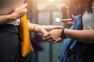 concept of working together two business women shaking hands in modern office for success
