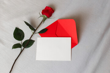 Red rose and envelope with copy space, laying on white bed. Valentine's day background, love and...