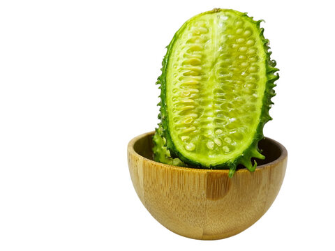 Cucumis anguria, cut in half in a wooden bowl, isolated on a white background. Known as maxixe. It is of African origin, belongs to the Cucurbitaceae family, something similar to the cucumber.