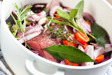 Beef rump cap with ingredients for brasato in a cooking pan