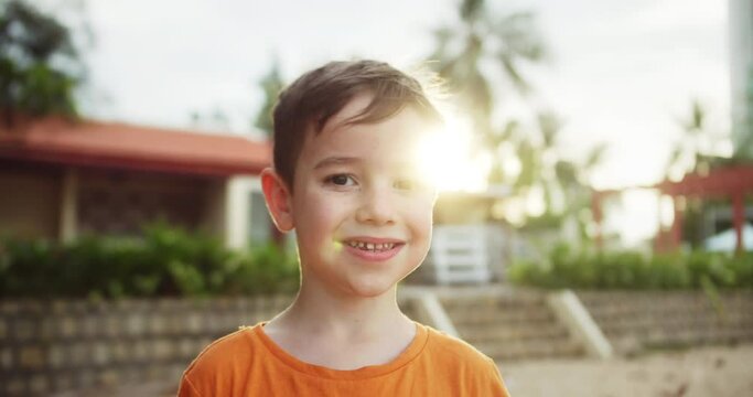 Portrait happy little boy in rays sun. Child smiles while looking at the camera. Boy dream. Face close-up. Happy child in park. Girl face in beach close-up. Dream girl. Happy face child.Beautiful face