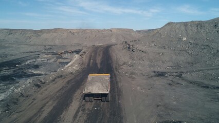 Camera moves after big dump truck loaded to the top with coal. Aerial view
