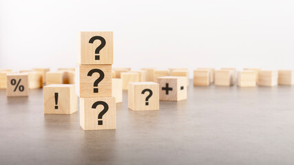 question mark shown on three wooden cubes on a gray background