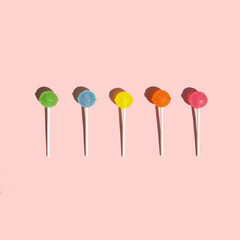 Colorful lollipops on pastel light pink background. Creative sweets composition. Minimal sugar concept.
