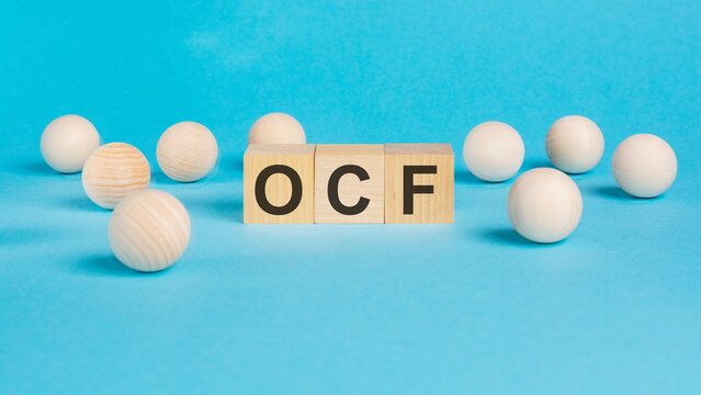 business concept. on the blue table wooden balls and wooden cubes with the inscription - OCF - Operating Cash Flow