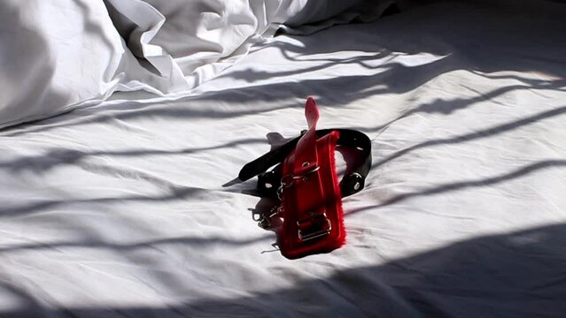 bdsm accessories falling on bed for couple sexual games. handcuffs and ball gag