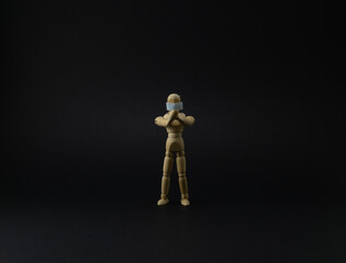 Wooden mannequin with protective surgical mask in black background