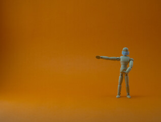 Wooden mannequin with protective surgical mask in orange backgound