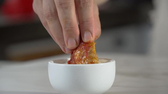 dipping buffalo wings into sauce