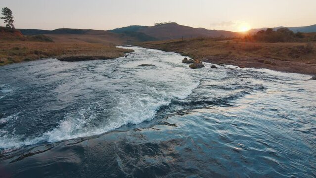 Rapid river flows in Brazilian mountains at sunset