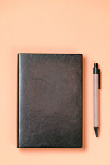 Black leather notebook on a paper orange background, notepad mock up, top view shot