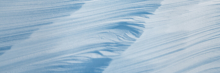 Fototapeta na wymiar Beautiful winter background with snowy ground. Natural snow texture. Wind sculpted patterns on snow surface. Arctic, Polar region.