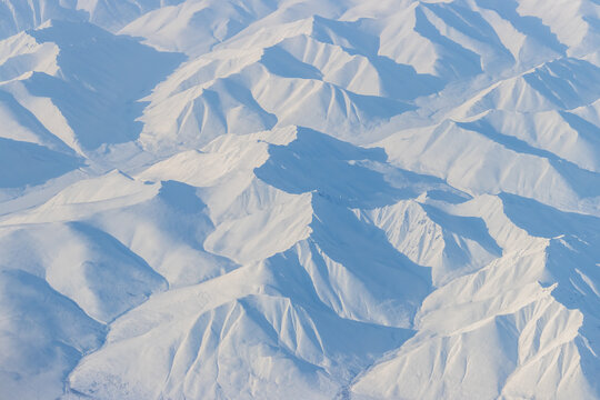 Aerial view of snow-capped mountains. Winter snowy mountain landscape. Travel to the far north of Russia. Kolyma Mountains, Magadan Region, Siberia, Russian Far East. Great for the background.