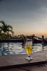 Poolside cocktail while people enjoy the summer vibes.