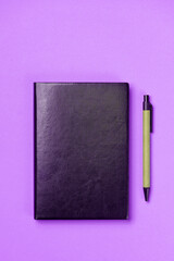 Black leather notebook on a paper pink background, notepad mock up, top view shot