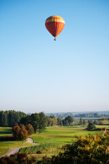 Colorful balloons fly over the green landscape of the field and trees