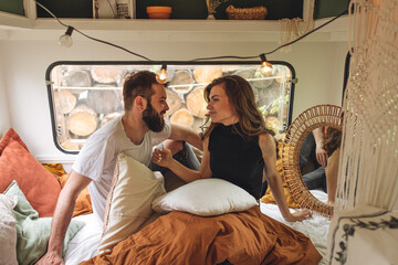 Young beautiful loving couple travelling across country in the van. Millennial man and woman in a travel camper. Cozy atmosphere, vacations vibe