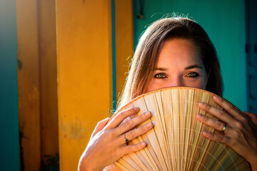 Retrato de mujer turista con sombrero vietnamita en las coloridas calles de la ciudad de Hoi An, en...