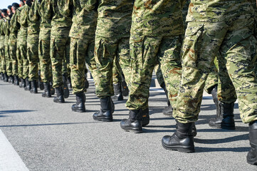 Soldiers in camouflage uniform and black boots marching in formation on parade. Special armed forces.  