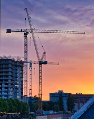 construction cranes at sunset with colorful sky background © A.R.