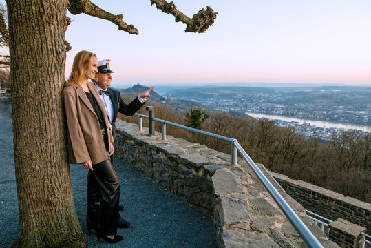 Eine junge, blonde Frau schaut gemeinsam mit einem deutschen Marinesoldaten auf dem Petersberg in Königswinter bei Bonn aufs Rheintal auf die Bonner Seite. Dabei lehnt sie sich an einen alten Baum und