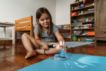 Child girl playing with crystals and torch light, learning about refraction during homeschooling 